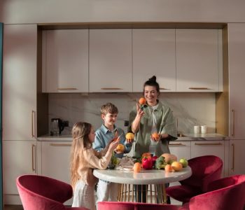 Mother with children preparing meals with fresh ingredients in a modern kitchen.
